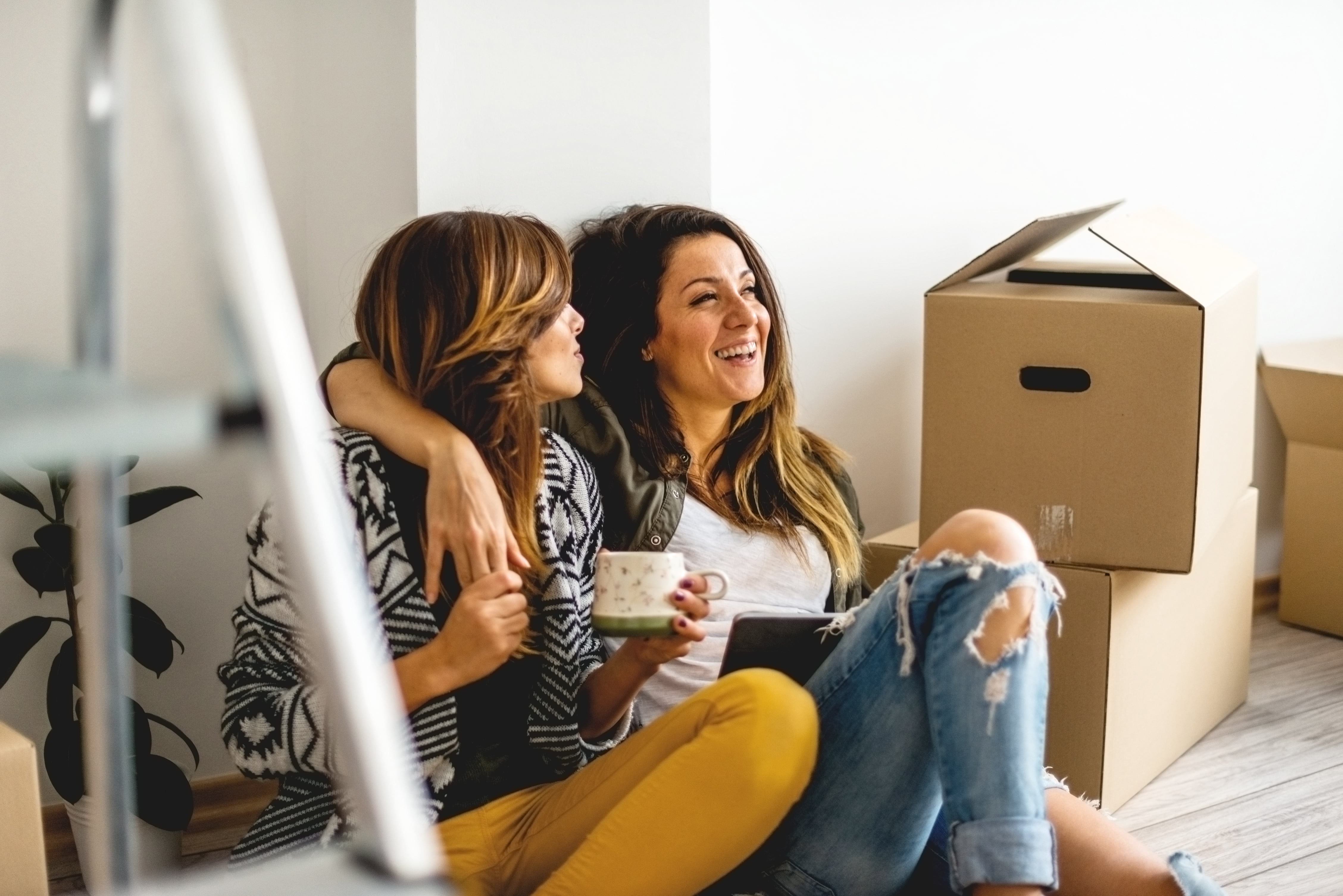 Mujeres sonriendo mudándose al rentar su hogar soñado.